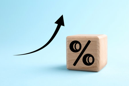 Percent sign on wooden cube and arrow against light blue backgroundの写真素材