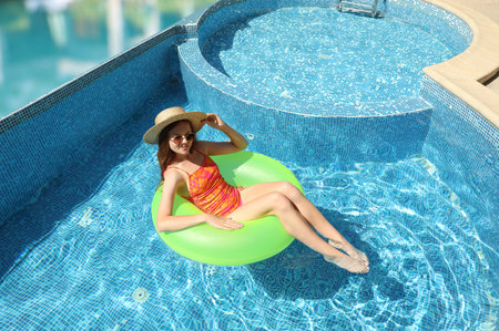 Girl with inflatable ring resting in swimming pool at sea resort