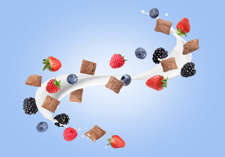 Splashing milk with sweet corn pads and fresh berries in air against blue gradient background. Healthy breakfastの写真素材