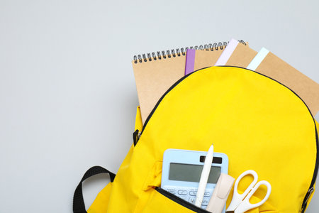 Yellow school backpack with different stationery on gray background, above view. Space for textの写真素材