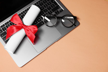 Diploma, laptop and glasses on beige table, top view. Space for textの写真素材