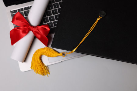 Graduation cap, laptop and diploma on light table, flat layの写真素材