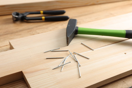 Metal nails, hammer, planks and pincers on wooden table, closeupの写真素材