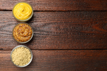 Different types of mustard on wooden table, flat lay. Space for textの写真素材