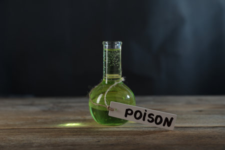Flask with poison on wooden table against dark background with smokeの写真素材