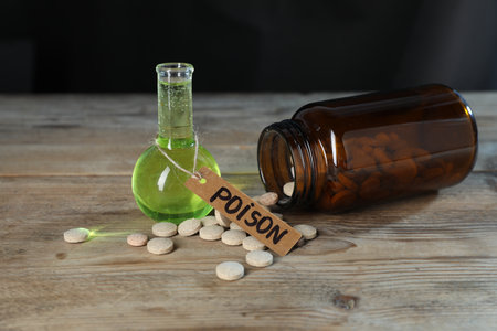 Bottles of poisons on wooden table against dark background, closeupの写真素材