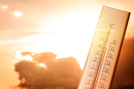 High temperature on thermometer against orange sky on sunny day. Hot summer weatherの写真素材