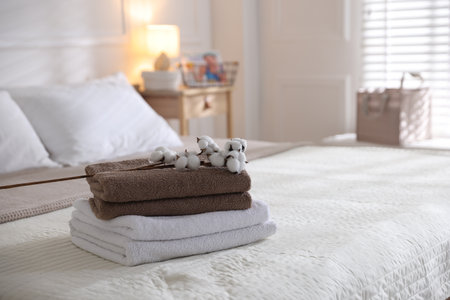 Stack of clean towels and cotton flowers on bed lines at homeの写真素材