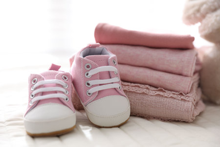 Stack of clean baby clothes and shoes on bed lines, closeupの写真素材