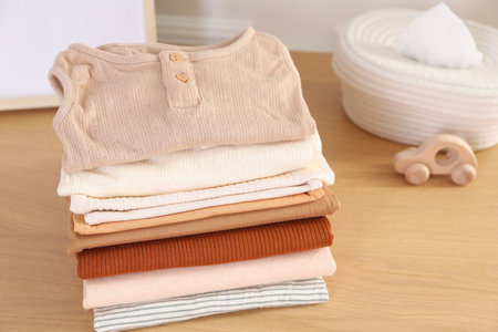 Stack of clean baby clothes on wooden table indoors, closeupの写真素材