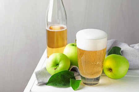 Fresh cider in glass, bottle and apples on white wooden table, closeupの写真素材