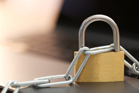 Cyber safety. Metal padlock with chain on laptop, closeup. Space for text