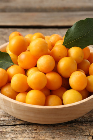 Ripe yellow cherry plums and leaves on wooden table, closeupの写真素材