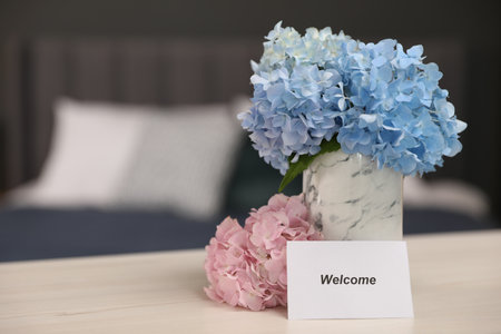 Card with word Welcome and hydrangea flowers on wooden table, space for textの写真素材