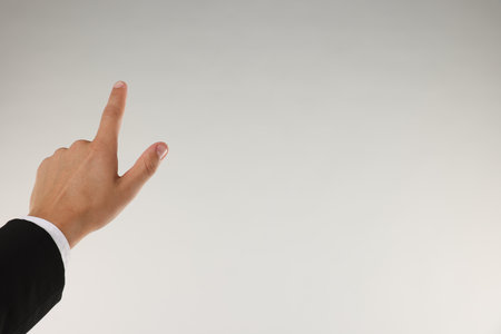 Man touching something on light grey background, closeup. Space for textの写真素材