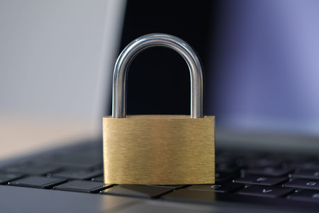 Cyber safety. Metal padlock and laptop on table, closeup