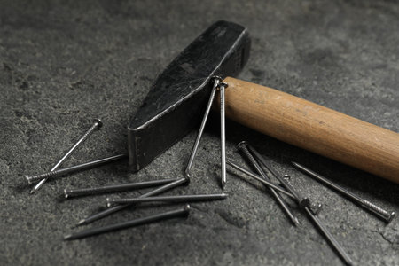 Hammer and metal nails on gray table, closeup