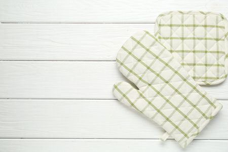 Oven glove and potholder on white wooden table, flat lay. Space for textの写真素材