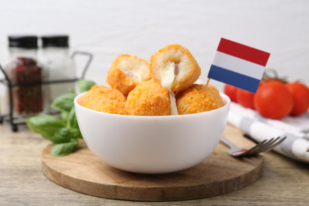 Delicious fried croquettes in bowl and flag of the Netherlands on wooden table, closeupの写真素材