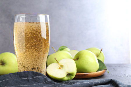 Fresh cider in glass and apples on black table, closeupの写真素材