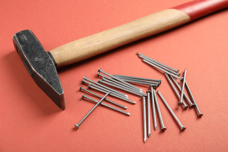 Metal nails and hammer on coral background, closeupの写真素材
