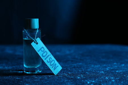 Bottle with poison on textured table against dark background, closeup. Space for textの写真素材
