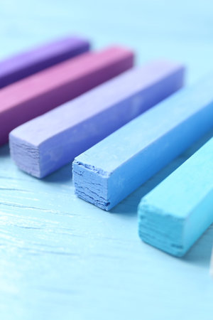 Colorful chalk pastels on light wooden table, closeup