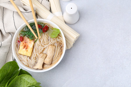 Tasty ramen with enoki and king oyster (eryngii) mushrooms on white table, flat lay. Space for textの写真素材