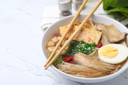 Tasty ramen with enoki and king oyster (eryngii) mushrooms on white table, closeup. Space for textの写真素材