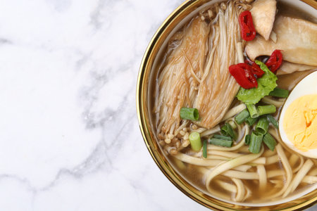 Tasty ramen with enoki and king oyster (eryngii) mushrooms on white marble table, top view. Space for textの写真素材