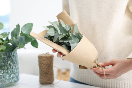 Florist making beautiful bouquet of eucalyptus branches at table in flower shop, closeupの写真素材