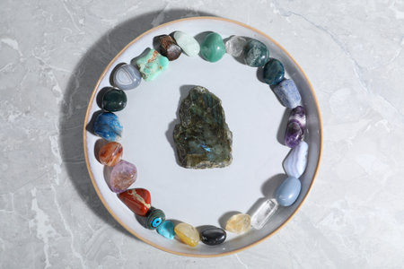 Many different healing stones on light gray table, top view