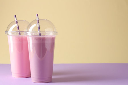 Tasty milkshakes in plastic cups on color background, space for textの写真素材