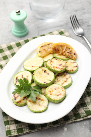 Delicious fried courgette slices with lemon and parsley served on gray table, closeupの写真素材