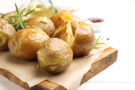 Tasty baked potatoes with rosemary served on white wooden table, closeupの写真素材