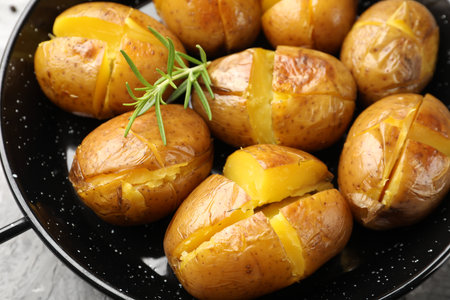 Tasty baked potatoes with rosemary served on light gray table, closeupの写真素材