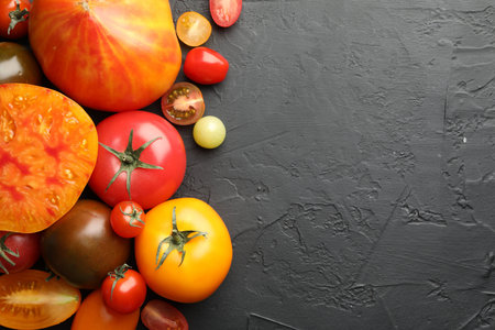 Different ripe tomatoes on black table, flat lay. Space for textの写真素材