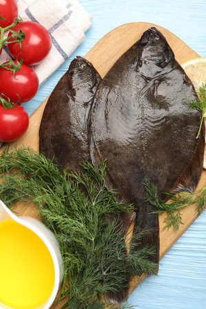 Fresh raw flounder fish and ingredients on light blue wooden table, flat lay. Seafood