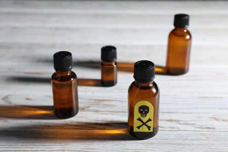 Bottles of poisons with warning sign on wooden table, closeupの写真素材