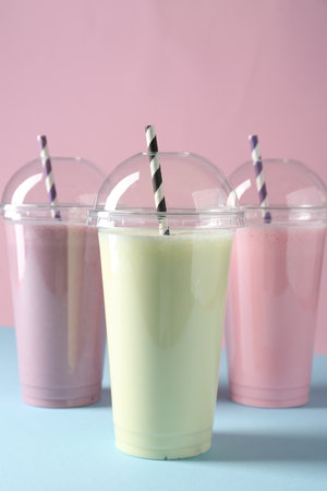 Tasty milkshakes in plastic cups on color backgroundの写真素材