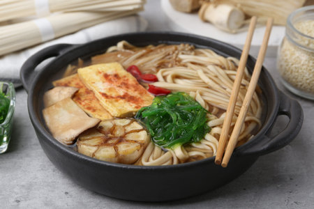 Tasty ramen with enoki and king oyster (eryngii) mushrooms on light gray table, closeup