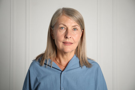 Portrait of beautiful senior woman near white wall