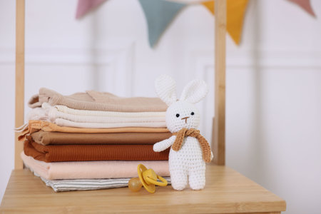 Stack of clean baby clothes and accessories on wooden dresser indoors, closeupの写真素材