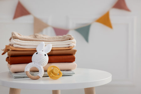 Stack of clean baby clothes and accessories on white table indoors, closeup. Space for textの写真素材