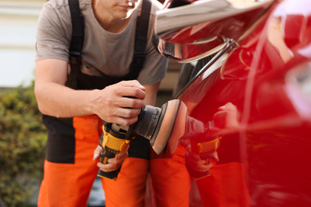 Man polishing car with orbital polisher outdoors, closeup