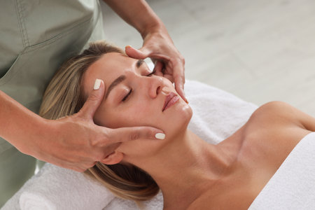 Beautiful woman receiving facial massage on couch indoors, closeupの写真素材