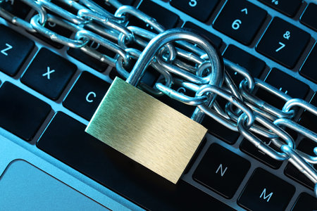 Cyber safety. Metal padlock with chain on laptop in color light, top view