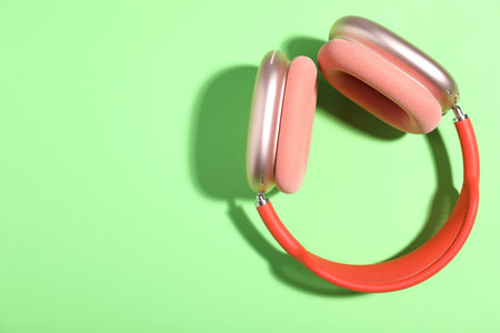 Pair of stylish pink headphones on light green background, top view. Space for textの写真素材