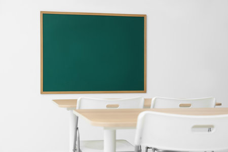 Blank green chalkboard, desks and chairs in classroomの写真素材