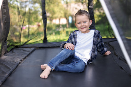 Happy little boy posing on black trampoline outdoorsの写真素材